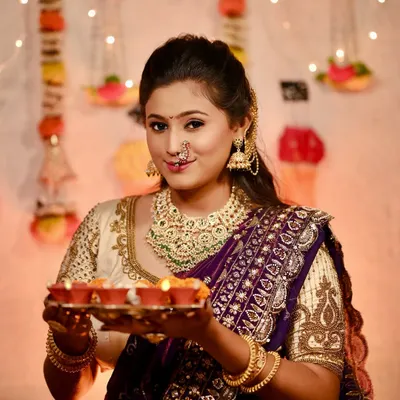 A perfect Diwali look. This model is holding a plate of diyas, wearing a rich purple Nauvari with a heavily embroidered cream blouse and matching jewellery.