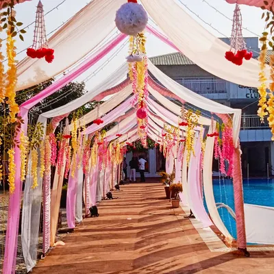 A beautiful draped walkway for a poolside event. I used flowing drapes in shades of pink, white, and yellow, with hanging floral strings to create a dreamy entrance path.
