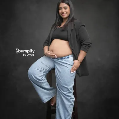 Maternity photos can be modern and chic too. This mom-to-be rocks a casual look with a blazer and jeans, showing off her beautiful bump with confidence and style against a classic studio backdrop.