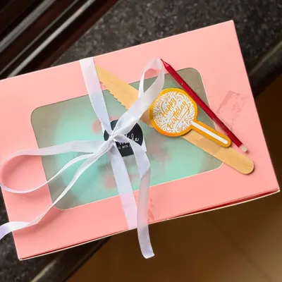 An example of my beautifully packaged bento cakes. This minimal light blue cake is presented in a pink box with a window, tied with a white ribbon, and includes a wooden knife and a birthday candle.