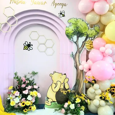 A sweet Winnie the Pooh themed Aqeeqa ceremony. This close-up shows the character cutout, beehive details, and a lovely mix of balloons and florals.