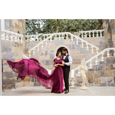 A classic fairytale pose on a grand stone staircase. The bride's magnificent purple gown with its long, flowing trail creates a moment of pure elegance and romance.