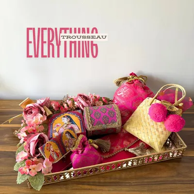 This is my "Everything Trousseau" tray in a regal Rani Pink. It’s a complete set for a bride, featuring a potli, cane bag, bangle case, and more, all curated to bring a touch of royal elegance to her new beginning.