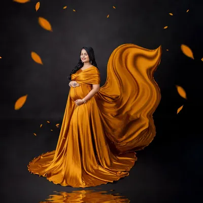 A moment of pure magic. Here, we used a stunning golden-mustard gown with a dramatic fabric toss and falling leaves to create a vibrant, artistic portrait against a classic black backdrop.