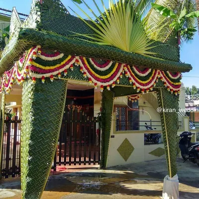 A traditional 'Chapara' entrance for a bride's home, intricately woven from green coconut leaves and decorated with flower garlands.