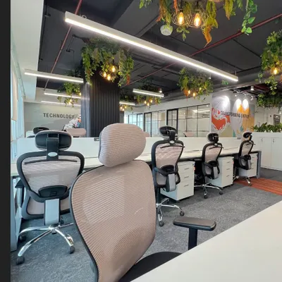 An open-plan workspace at the Rays Power office, featuring ergonomic chairs and integrated planters on storage units. We incorporated biophilic design with hanging plants to improve air quality and create a calming atmosphere for employees.