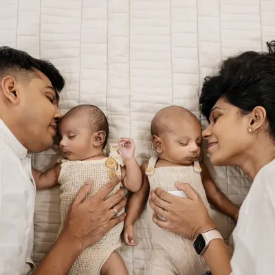 Capturing the complete family with newborn twins is a special honor. This lifestyle portrait shows the beautiful bond and symmetry as parents gaze lovingly at their babies.