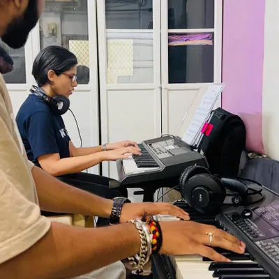 A student receives guidance from a coach during a keyboard lesson. This side-by-side teaching approach ensures that students learn correct posture and hand positioning from the very beginning.