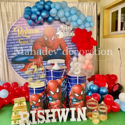 An action-packed Spiderman theme for a third birthday. This setup features a large circular backdrop with a brick wall and Spiderman graphic, themed pedestals, and a red and blue balloon arrangement.