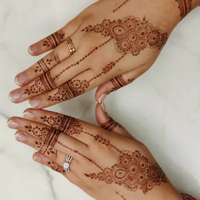 A stylish and minimal Arabic design, perfect for an engagement party guest. The pattern flows diagonally across the back of the hand, with simple bands on the fingers.