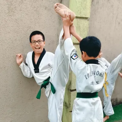 This student's incredible flexibility is the result of consistent practice. Partner-assisted stretches like this help push boundaries safely and improve kicking height.