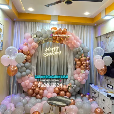 A beautiful circular balloon arch in pastel pink, grey, and rose gold. The "Happy Birthday" neon sign in the center makes it a perfect, modern backdrop for a birthday party.