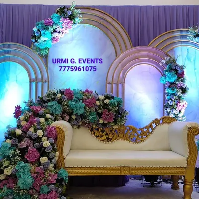 A breathtaking anniversary stage with a cascade of purple, blue, and pink flowers over an elegant white sofa. This style is perfect for couples looking for a rich and romantic floral theme for their celebration.
