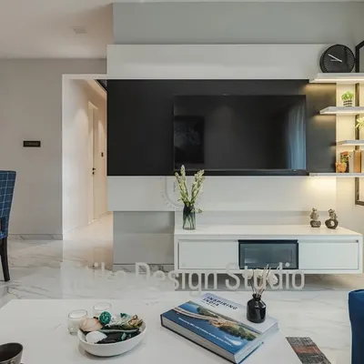 This close-up shows the details of the custom media unit. The combination of a black panel, a floating white console, and open, backlit shelving creates a design that is visually light yet provides ample space for electronics and decor.