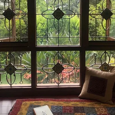 This wide window at the Roopa Hariprasad Residence features a custom-designed grille with floral motifs and inlaid tiles. It frames the view of the garden beautifully, turning the window itself into a piece of art.