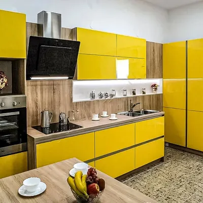 A cheerful and modern kitchen featuring bright yellow high-gloss cabinets. The wood accents and integrated appliances balance the bold color for a stylish finish.