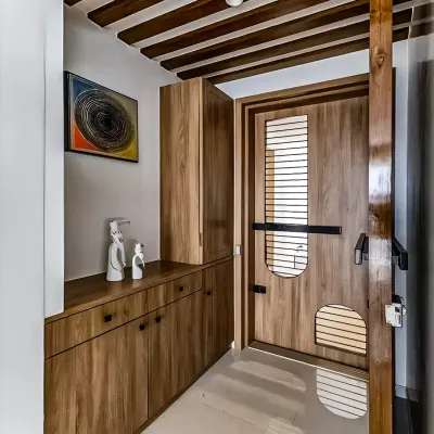We designed this entryway with floor-to-ceiling wooden storage, including a console table with drawers and a tall cabinet. The custom-designed main door with slatted details complements the furniture, creating a warm and cohesive entrance.