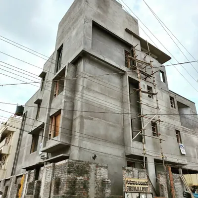 A residential building in Giriraja Layout, shown with its final plastering complete. The raw concrete form is celebrated, showcasing the building's strong, sculptural lines before the final paint and finishes are applied.