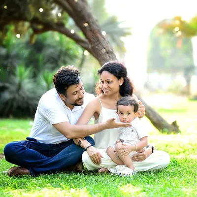 A beautiful family enjoying a relaxed moment in the park. The warm sunlight filtering through the trees creates a magical, golden-hour glow, perfect for a candid lifestyle photoshoot.