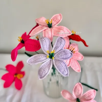 I'm so excited to launch my new crochet lily flowers. This photo shows them in four different shades: baby pink, vibrant pink, lavender, and red, displayed in a simple glass.