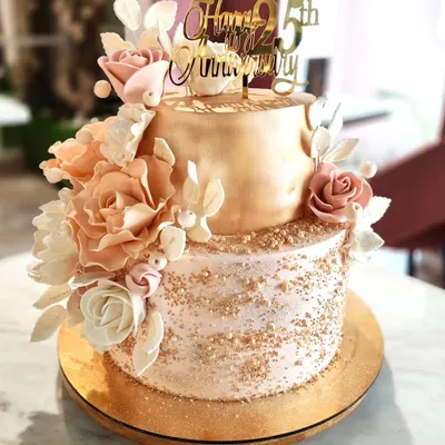 A full view of the 25th-anniversary cake, showcasing the cascade of hand-sculpted sugar flowers against the two-tone metallic and textured buttercream finish.