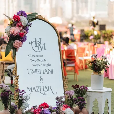 A modern and romantic welcome sign for a Mehendi. We combined a chic mirror with a beautiful floral arrangement and a playful quote, "All Because Two People Swiped Right," to personalize the entrance.