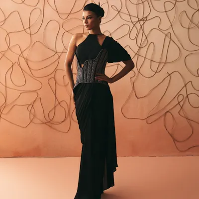 The Nexus gown reimagines the sari with a pre-stitched drape that slips on with ease, anchored by a sculpted corset belt. Here, asymmetry finds balance, and every line recalls the bonds we stitch and the ones we let loosen.