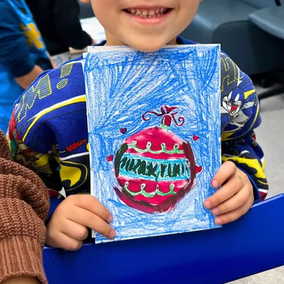 Getting into the holiday spirit with some handmade Christmas cards! A kindergarten student proudly shows off his colorful ornament drawing from one of our recent workshops.