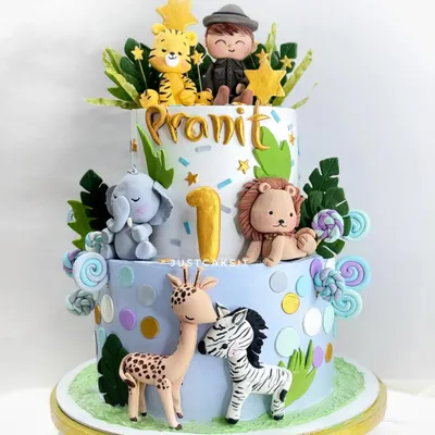 A beautiful two-tier cake for a first birthday, featuring a whole family of cute, hand-molded jungle animals and a little boy figurine.