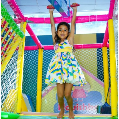 A happy child confidently navigates the monkey bars in our colorful indoor play gym. The entire structure is padded and enclosed with safety netting.
