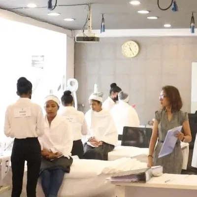 Students participating in a practical skin care examination. The setup mirrors a professional salon environment, preparing them for real-world job scenarios.