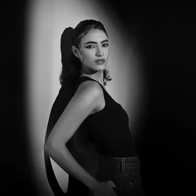 A classic black and white portrait using a single spotlight. The dramatic shadow and the model's intense gaze create a timeless, cinematic feel.