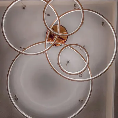 A modern chandelier featuring interlocking rings of light. This fixture is more than just a light source; it's a sculptural element that adds a contemporary artistic touch to the office cabin it illuminates.