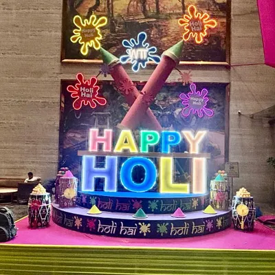 We created this vibrant, large-scale installation for a Holi celebration, featuring custom-lit 'Happy Holi' lettering and oversized pichkari props. This type of illuminated centerpiece becomes the focal point for any festive gathering.