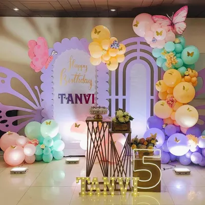 A beautiful pastel butterfly theme for a 5th birthday, featuring a custom backdrop, marquee letters, and large butterfly wing cutouts.