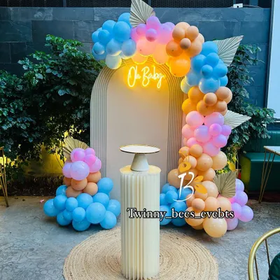 A trendy boho-style baby shower setup. We used a modern arched backdrop with an "Oh Baby" neon sign, surrounded by a beautiful balloon arrangement in pastel blue, pink, and orange.