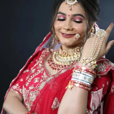 A classic bridal pose showcasing the complete look. The bold pink eyeshadow, perfectly blended foundation, and traditional jewelry come together to create a stunning and memorable wedding day appearance.