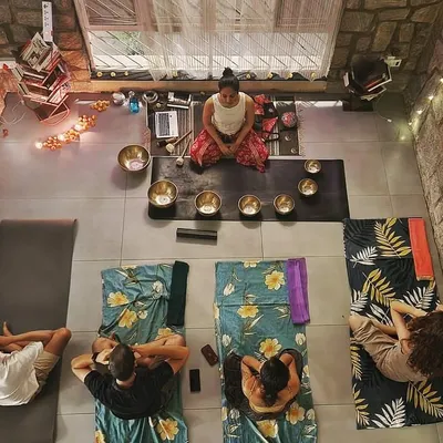 An aerial view of an intimate sound bath session held in a beautiful stone-walled studio. Participants are resting comfortably as one of my certified students facilitates the session, demonstrating the supportive community we build.