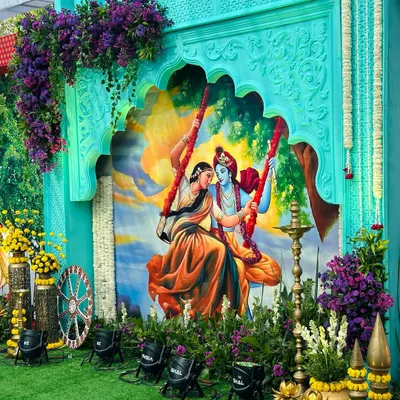 The centerpiece of our Vrindavan theme: a beautiful painting of Radha and Krishna on a swing, framed by a custom-carved arch and lush floral decor.