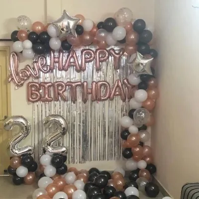 A popular room decoration setup for a 22nd birthday. This features a silver foil curtain, "Happy Birthday" and "love" foil letters, and a balloon arch in rose gold, black, and white.