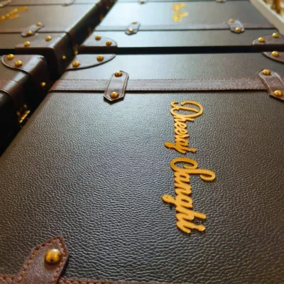 A row of dapper leatherette trunks, each personalized with a name in gold acrylic. These were created to celebrate a 20-year partnership between Axis Bank and Yes Bank, serving as a sophisticated employee recognition gift.