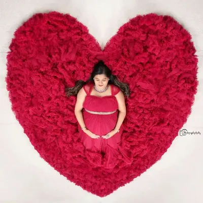 Our signature overhead studio shot, with the mother-to-be peacefully lying in a heart-shaped arrangement of a red ruffled gown.