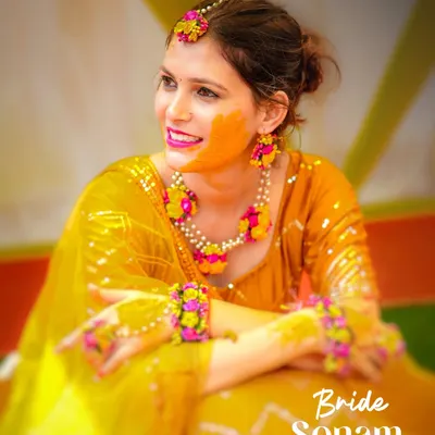 A beautiful bride smiling during her Haldi ceremony, with turmeric paste on her cheek. We capture the joy and tradition of this vibrant pre-wedding event.