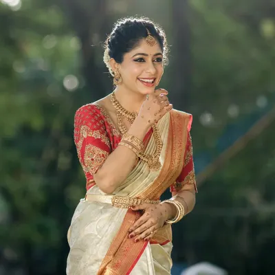 This bride looks radiant in a classic red and cream Kanjivaram saree. I designed a matching red blouse with rich gold embroidery on the sleeves and a modern transparent back, blending tradition with a contemporary touch.