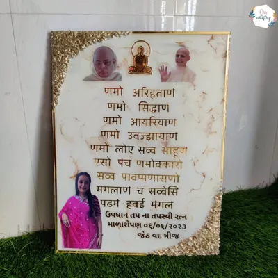 A custom Navkar Mantra frame featuring photos of revered figures and a loved one. The white marble resin is accented with a gold geode border.