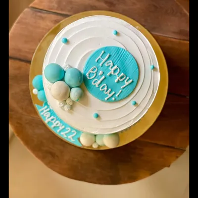 A minimal and modern birthday cake in shades of blue and white, decorated with chocolate spheres.