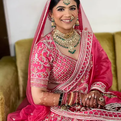 The pure joy on a bride's face is everything. For this look, I created a classic bridal updo to sit neatly under her dupatta, complementing her stunning pink lehenga.