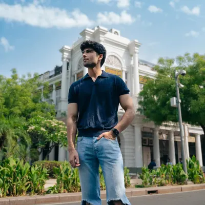 A full-length outdoor shot of a model in casual ripped jeans and a polo shirt, set against classic architecture. This image showcases a confident, relaxed look for a lifestyle portfolio.