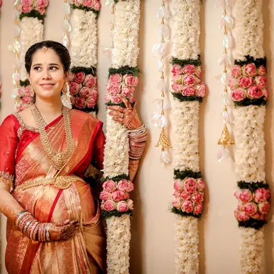 A beautiful solo portrait of the mom-to-be during her baby shower. Dressed in a stunning silk saree and traditional jewelry, she stands before an elegant floral backdrop.