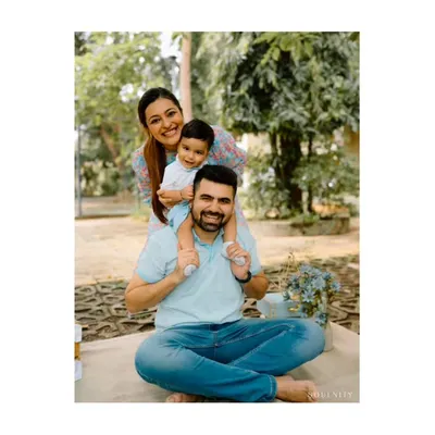 A playful "family stack" portrait during an outdoor session. The son on his dad's shoulders and the mom peeking from behind creates a fun, dynamic, and loving image.